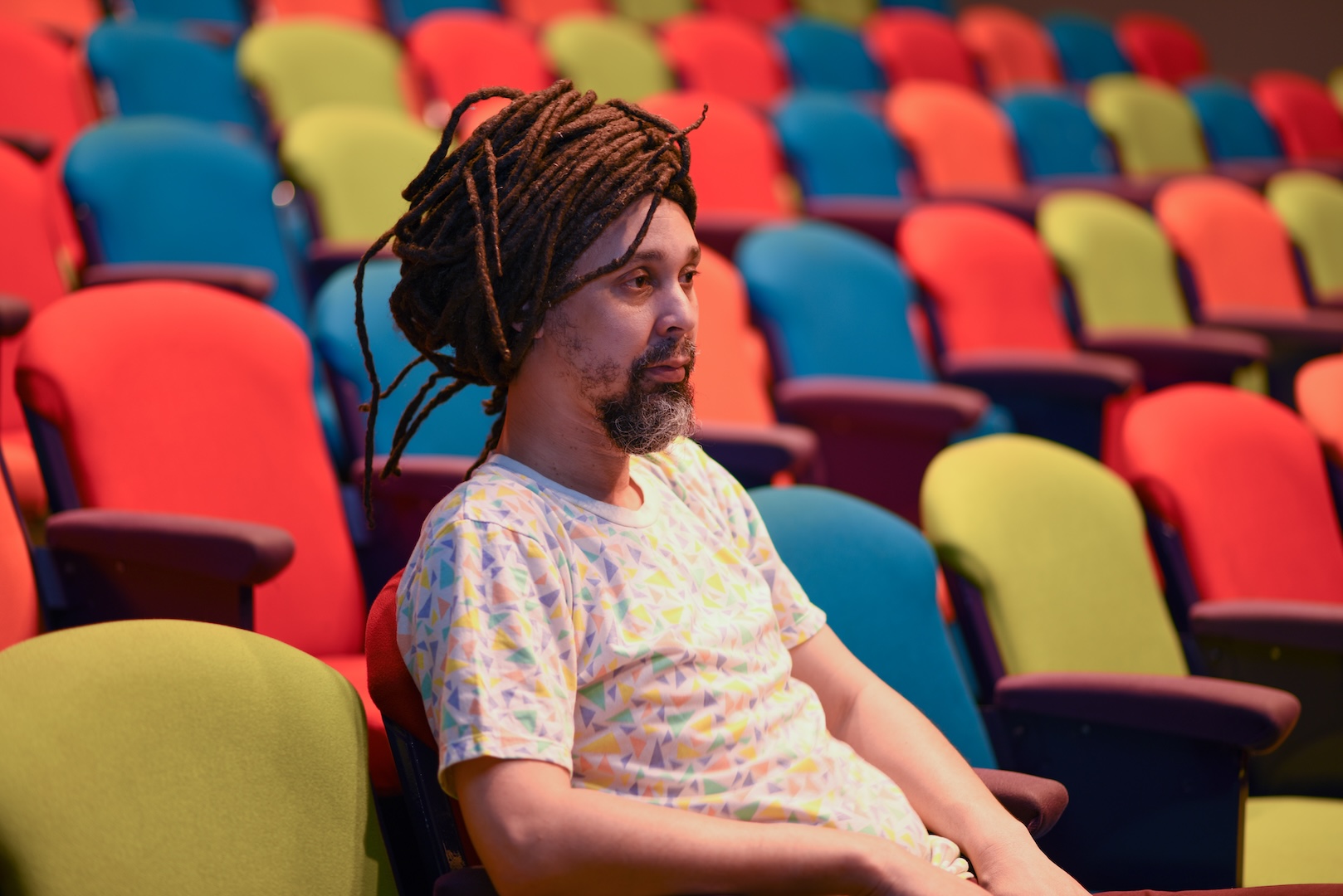  A person sitting alone in a setting with rows of seats, like a theatre